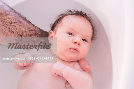 Parent bathing baby, cropped