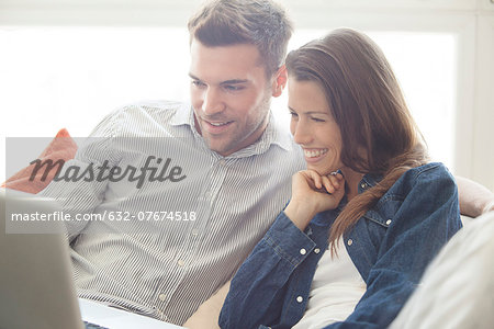 Couple relaxing at home looking at laptop computer together