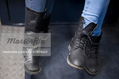Women sitting together on subway train, close-up of boots