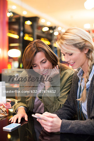 Women looking down at cell phone together