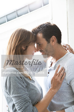 Couple touching noses and embracing by open window Couple touching noses and embracing by open window