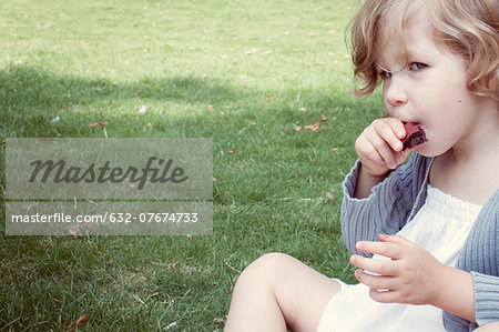 Little girl eating sweet snack outdoors