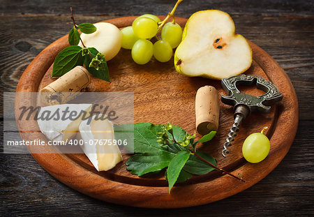 Wine frame background. Cheese and fruit on a wooden serving board.