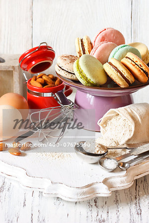 Delicious macarons on a cake stand and fresh ingredients for baking.