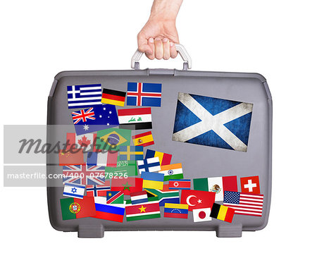 Used plastic suitcase with lots of small stickers, large sticker of Scotland