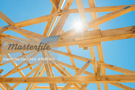 New residential construction home framing against a sunny sky.