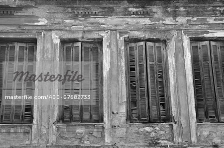 Broken wooden window shutters and textured wall of an abandoned house. Urban decay black and white.