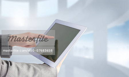 Businesswoman using a tablet pc against bright white room with windows