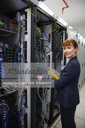 Happy technician using digital cable analyzer on server  in large data center