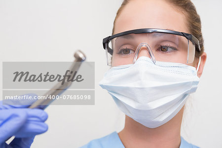 Dentist in surgical mask and protective glasses holding drill at the dental clinic