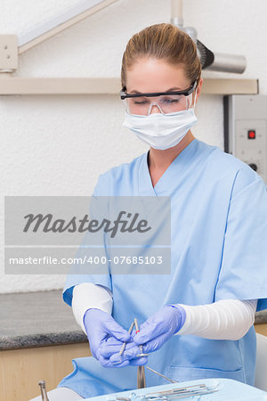 Dentist in blue scrubs holding dental tools at the dental clinic