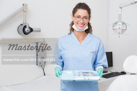 Dentist in blue scrubs holding tray of tools at the dental clinic