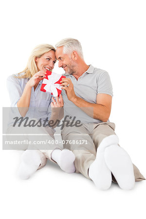 Happy couple sitting and holding present on white background