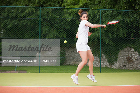 Pretty tennis player playing on court on a sunny day