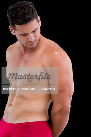 Side view of a shirtless muscular man posing over black background