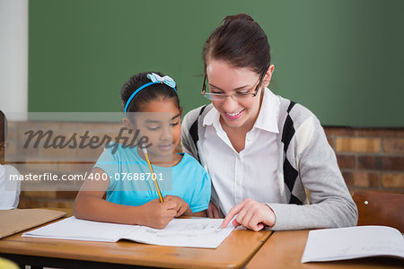 Pretty teacher helping pupil in classroom at the elementary school