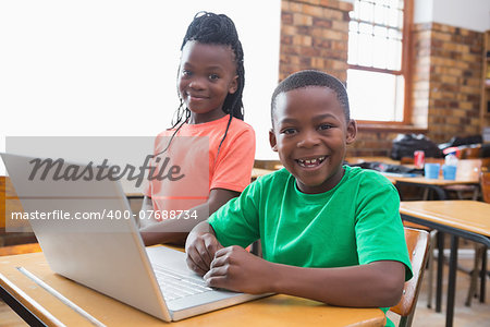 Cute pupils using laptop in classroom at the elementary school