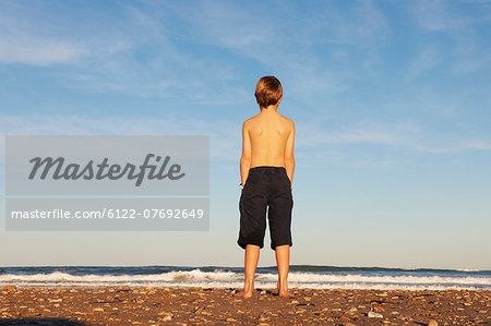 Boy on beach looking out to sea