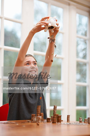 Girl emptying her piggy bank of coins