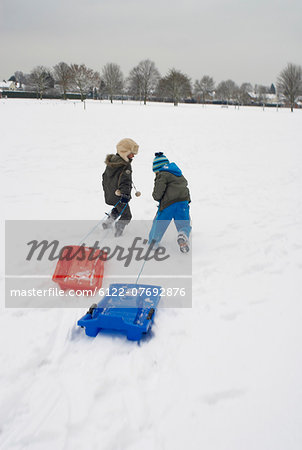 Boys running in snow with sledges