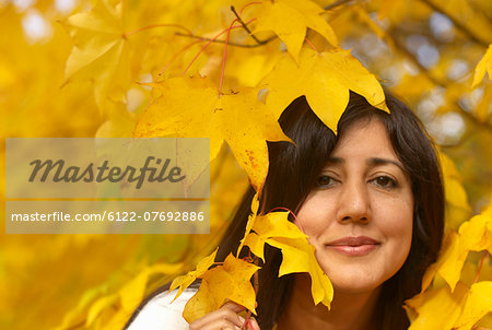 Woman looking through leaves in autumn