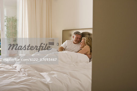 Mature couple embracing tenderly in bed