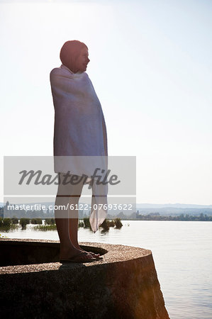 Young girl wrapped in towel by lake
