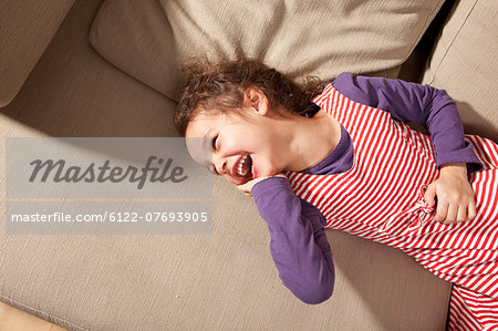 Little girl lying on couch laughing