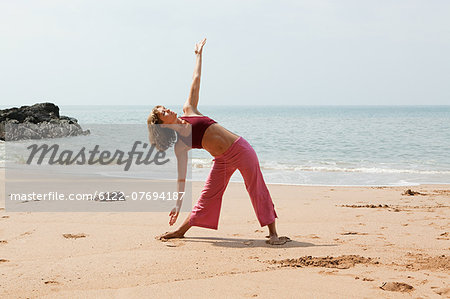 Woman practicing yoga on a beach