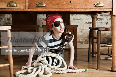 Young girl dressed up as pirate, under desk