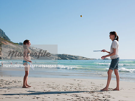 Mother and daughter playing paddleball on beach