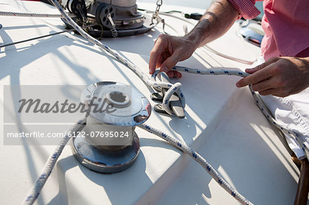 Mid adult man on board yacht holding rope