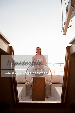 Mid adult man steering yacht