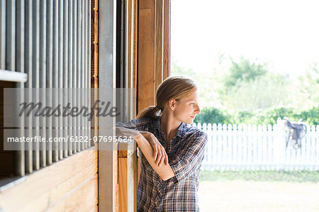 Mid adult woman in stable, looking away