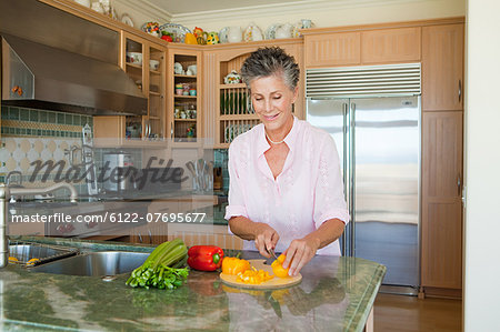 Senior woman chopping peppers in kitchen