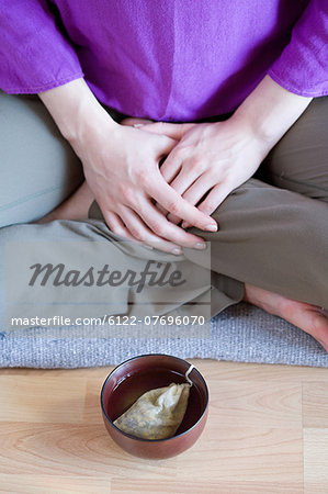 Woman sitting cross legged with teacup on floor