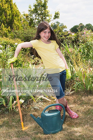 Girl in garden with rake and watering can