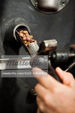 Man using coffee grinder, close up of coffee beans