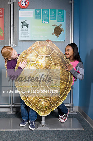 Two girls standing behind green sea turtle shell