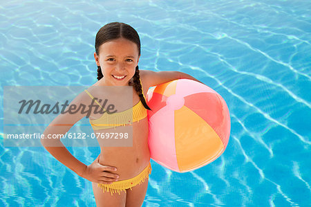 Girl with beach ball by swimming pool, portrait