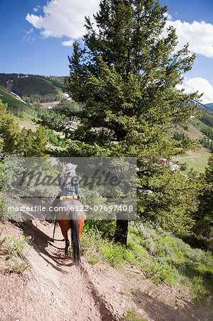 Woman horse riding through Beaver Creek, Colorado, USA