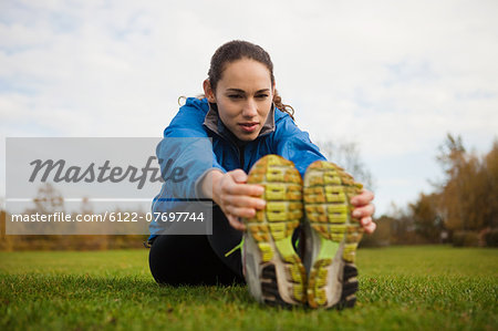 Young woman performing stretches in park