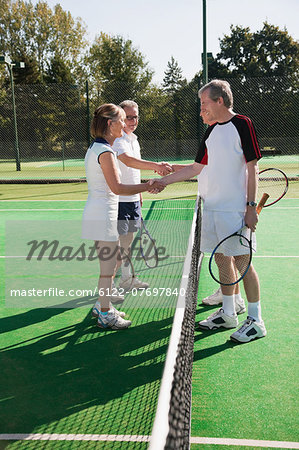 Senior and mature adults shaking hands on tennis court