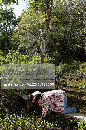 Mother and daughter kneeling on boardwalk in forest