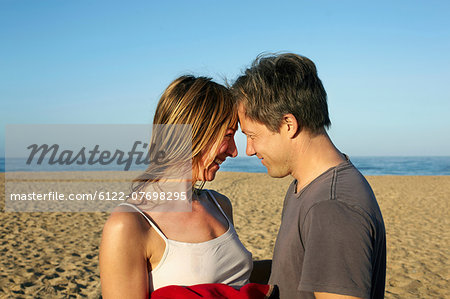 Mid adult couple relaxing head to head on beach