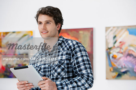 Young man using digital tablet in art gallery