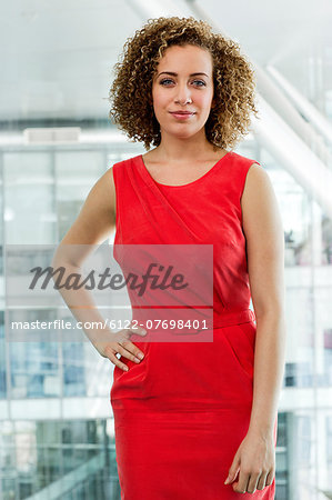 Portrait of young businesswoman in red dress in office