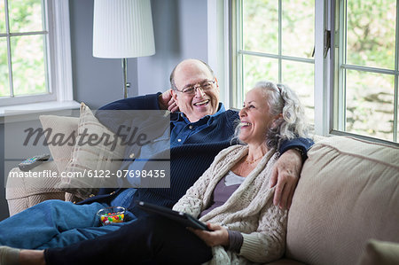 Senior couple using digital laptop on sofa at home