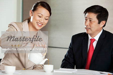 Businesswoman pouring tea for businessman