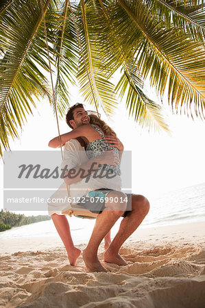 Couple hugging on swing at beach